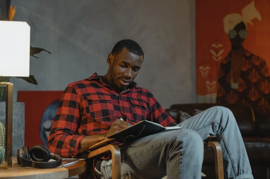 Una persona che scrive idee per un'app su un taccuino in un ambiente di lavoro creativo.